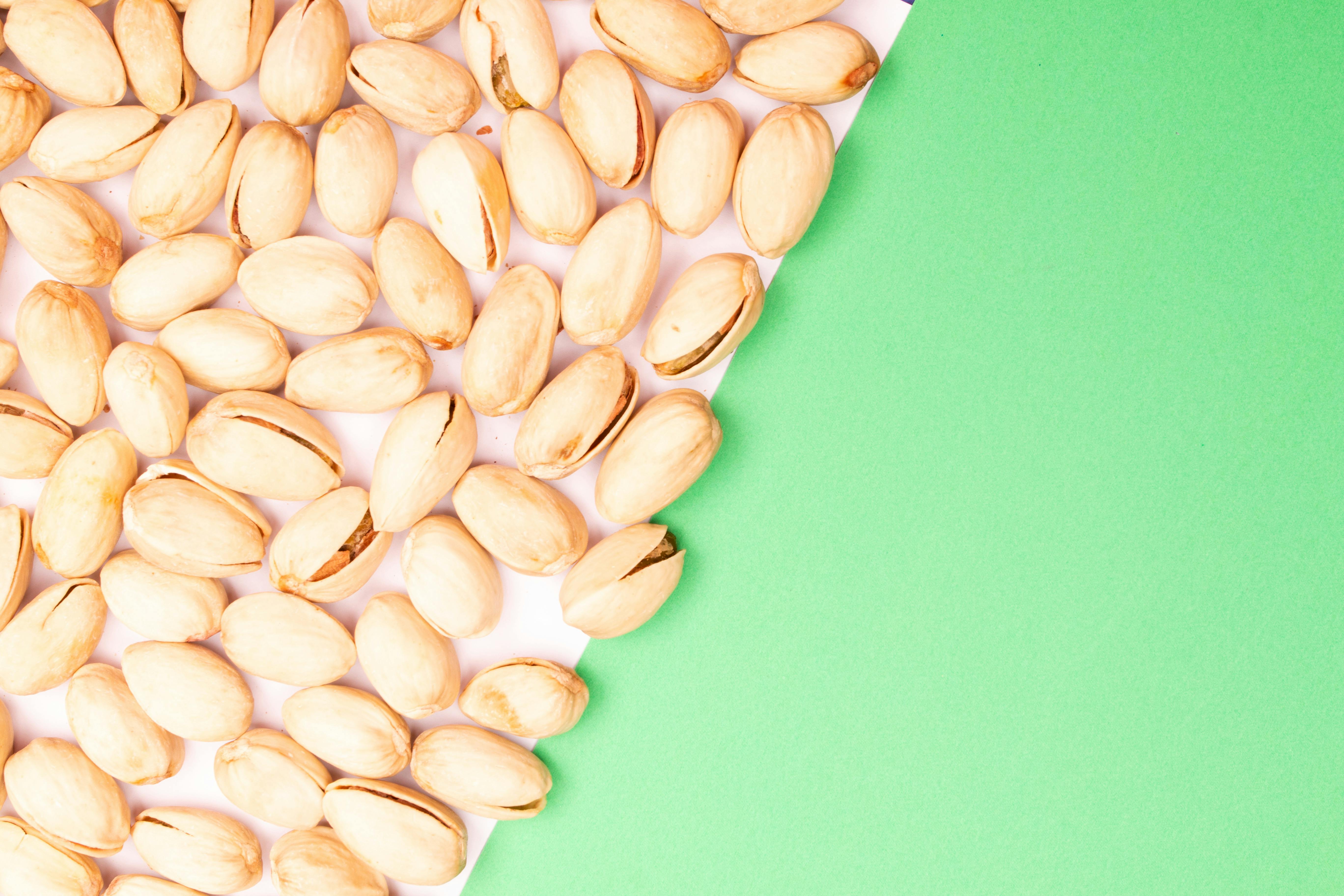Top view of organic pistachios scattered on a green surface.