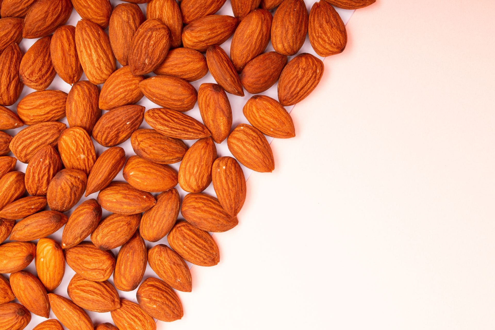 A vibrant close-up image of roasted almonds on a white background, showcasing texture.