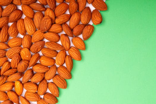 Close-up of organic almonds scattered on a green background, ideal for healthy eating concepts.