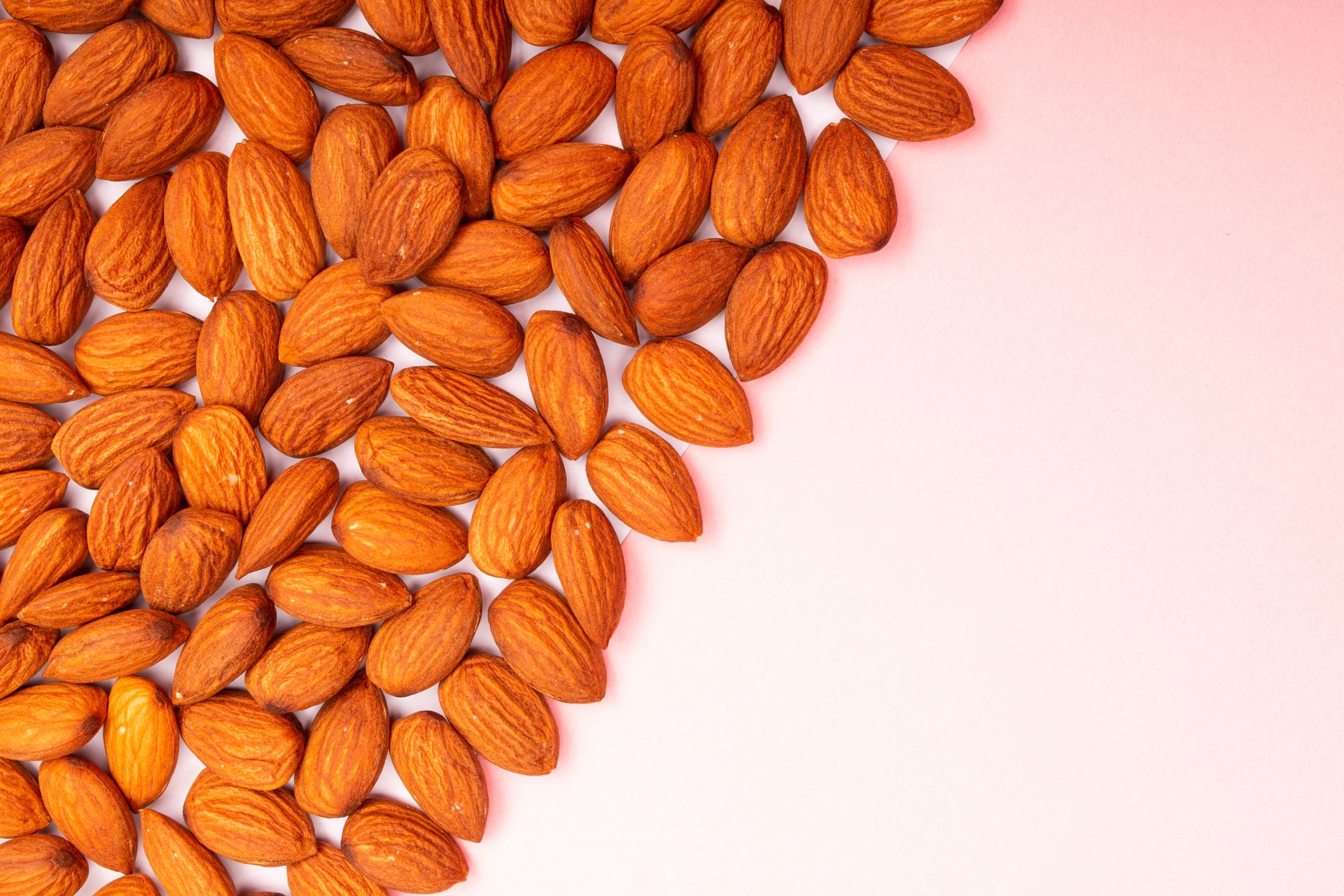 Close-Up Shot of Almond Nuts on a Pink Surface