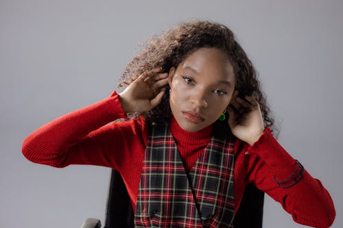 Woman in Red Sweater with Hands on Head