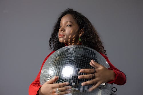 Free Woman in Red Sweater Holding a Disco ball Stock Photo