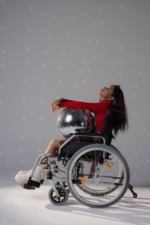 A Young Woman in a Wheelchair Holding a Disco Ball