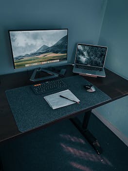 Modern workspace featuring a desktop monitor, laptop, keyboard, and mouse on a stylish desk.