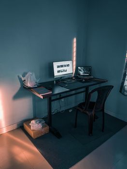 A minimalist home office setup with dual monitors, chair, and desk under soft lighting.