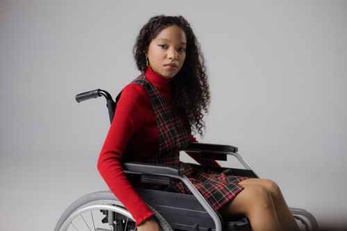 Free Stylish young black woman in wheelchair posing confidently in a studio setting. Stock Photo