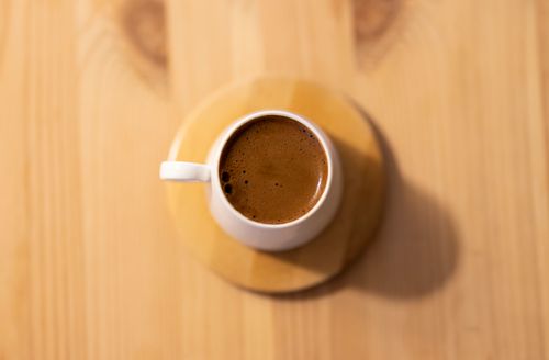 Free Minimalist coffee scene with a white mug on a wooden table captured from above. Stock Photo