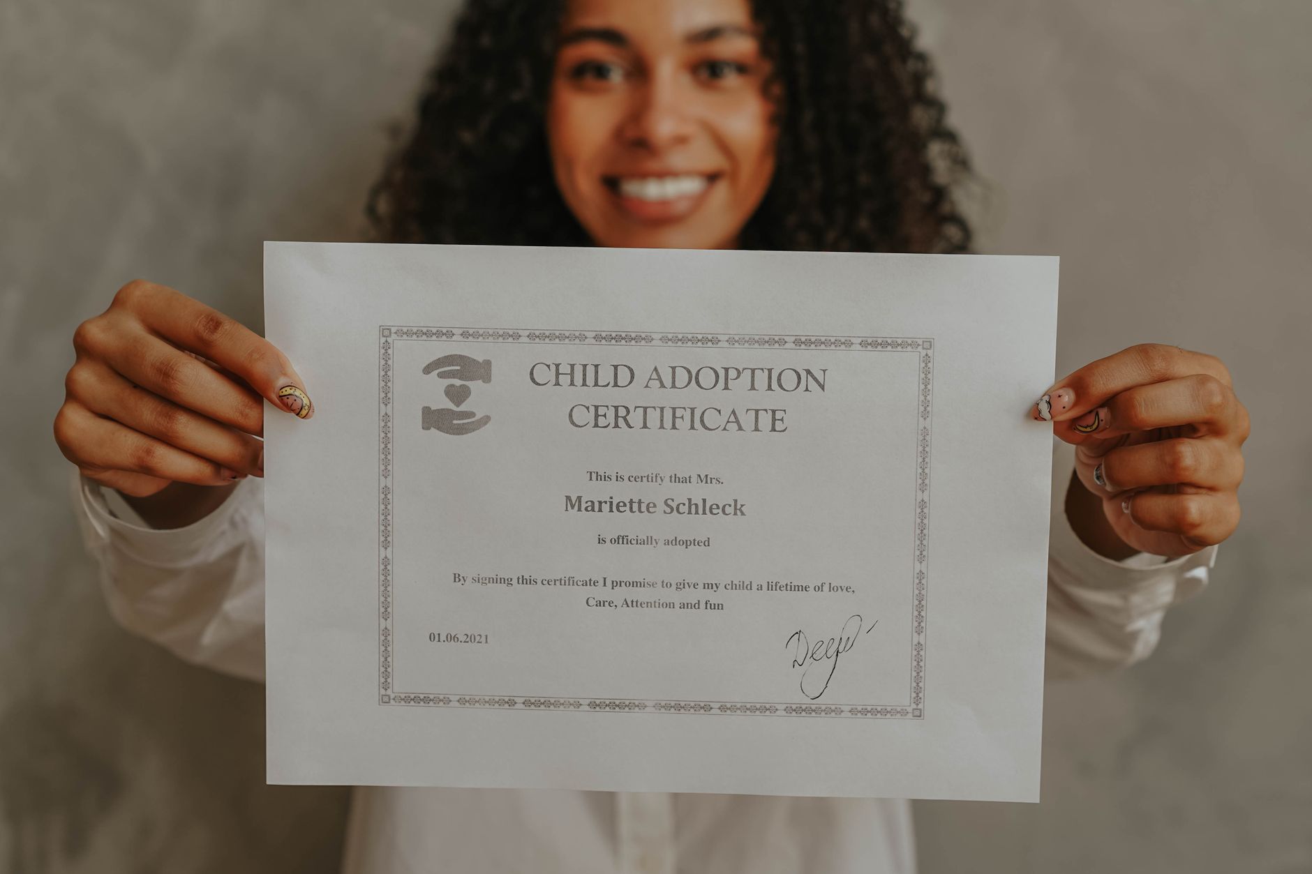 Smiling woman proudly displays an adoption certificate.
