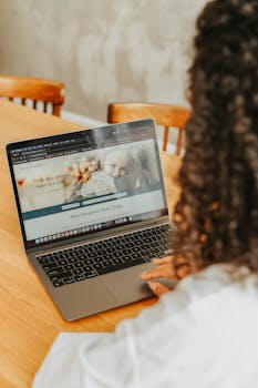 A person browses adoption resources on a laptop indoors, highlighting home study environment.