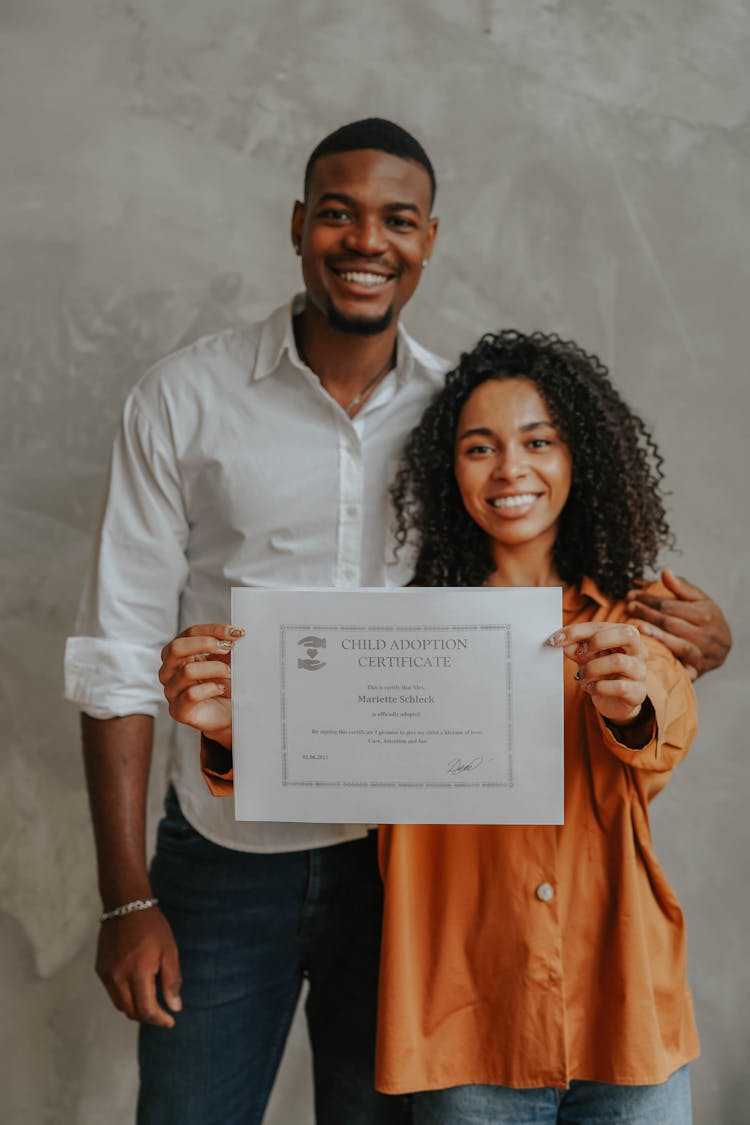 A Couple Holding An Adoption Certificate