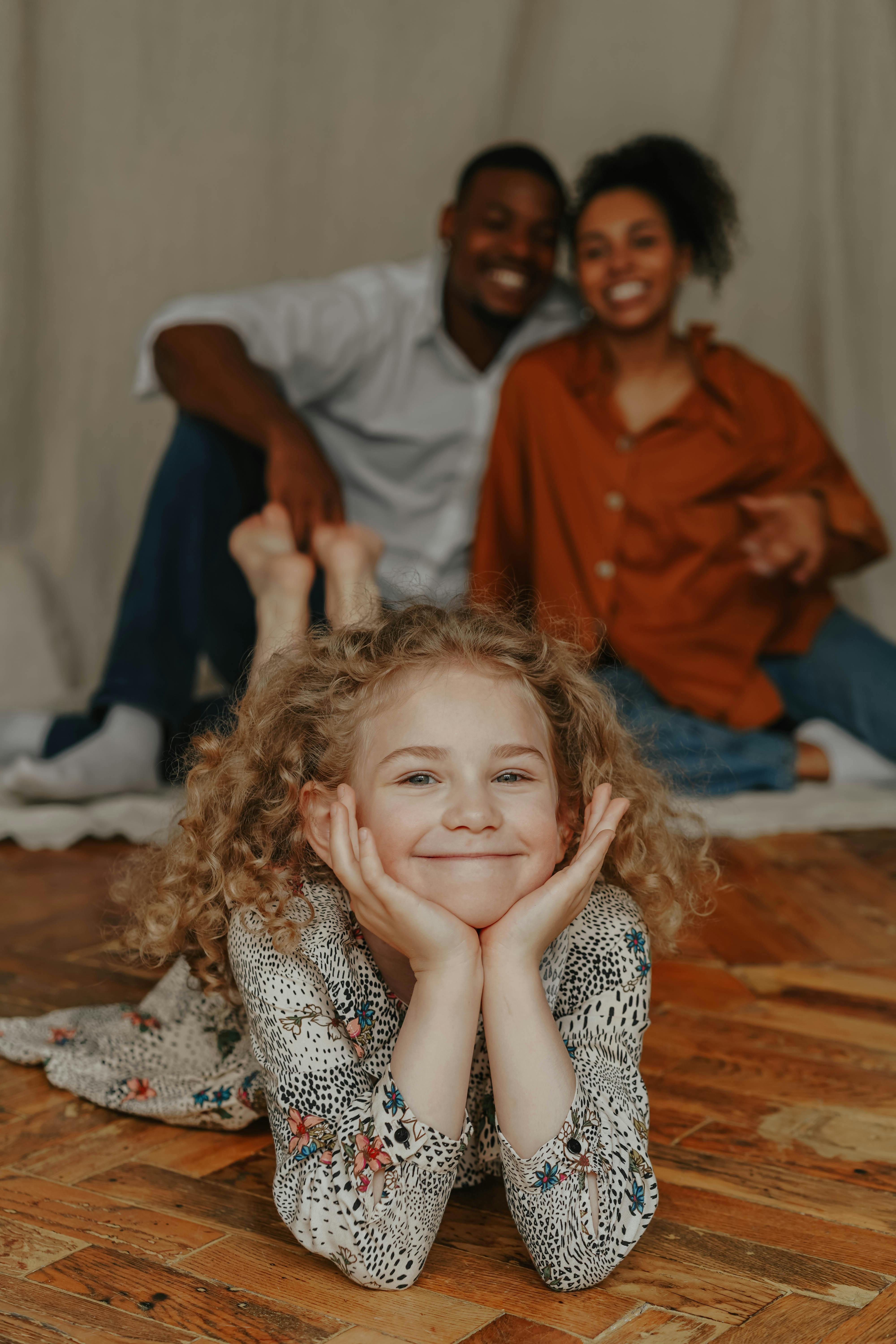 Cheerful family portrait with young girl posing happily at home.