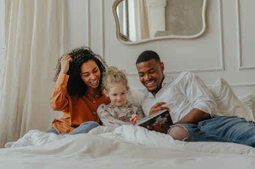 Free A Family Reading a Book on the Bed Stock Photo