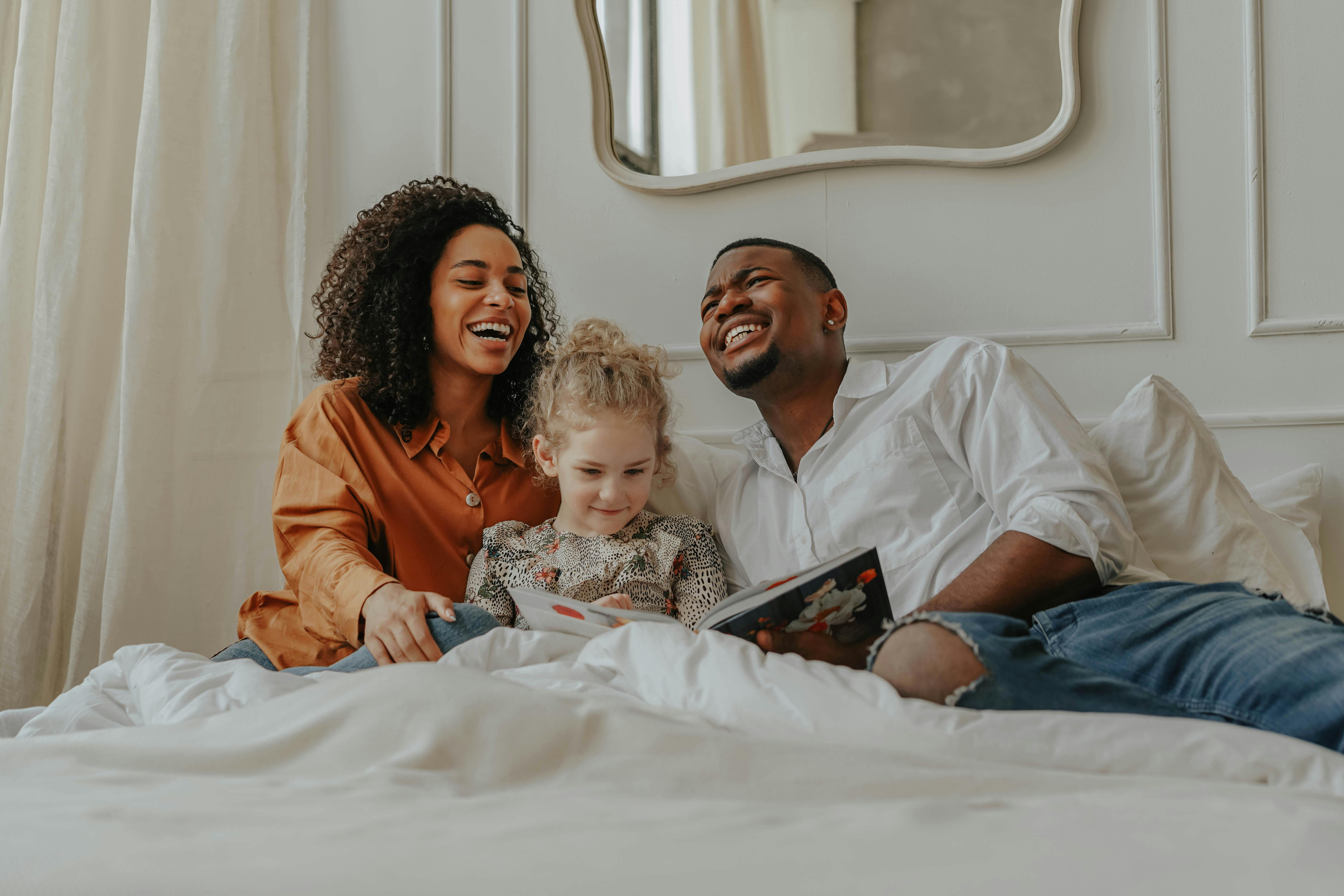 parents sitting on the bed with their daughter