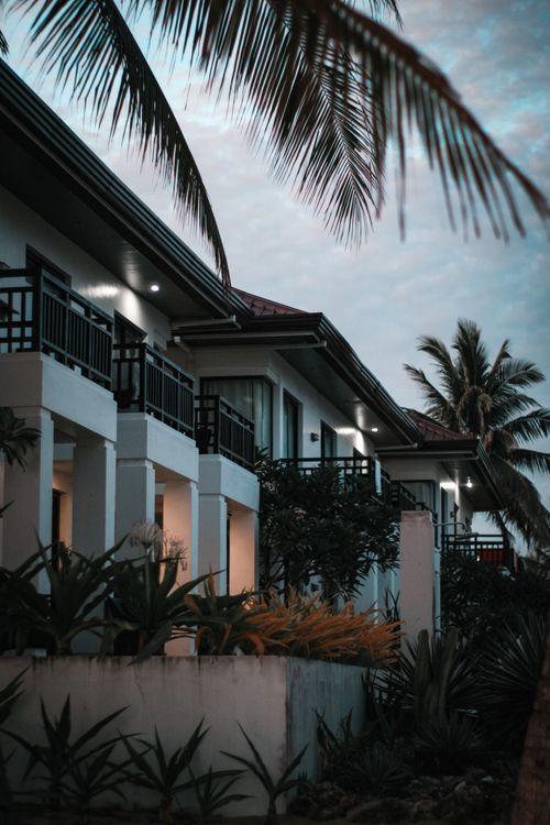 Free Elegant resort building with palm trees at twilight, creating a tranquil tropical atmosphere. Stock Photo