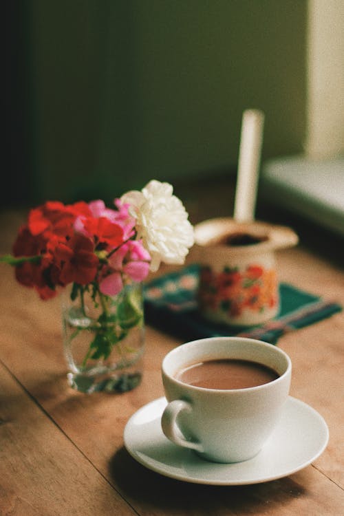 Cup of Coffee Beside a Flower Vase