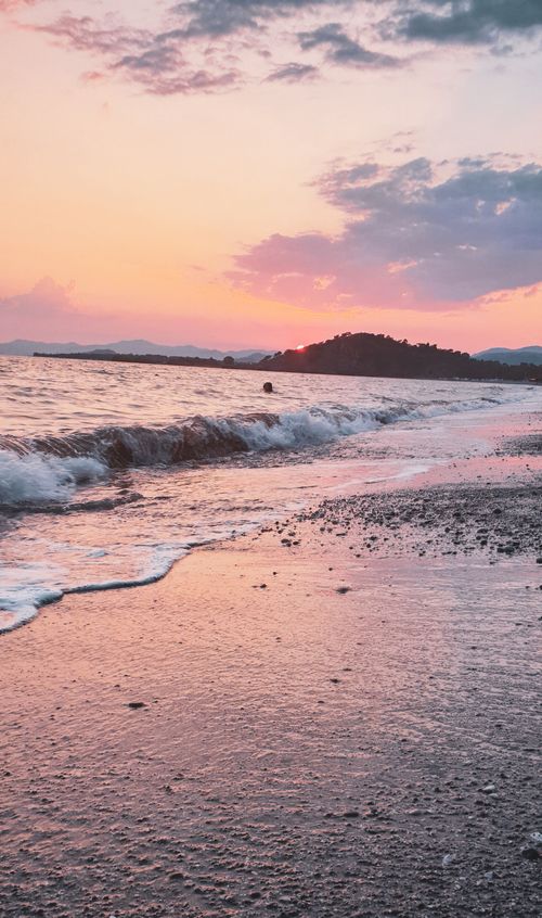 Free A breathtaking sunset on a quiet beach, highlighting waves and colorful sky. Stock Photo