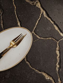 An elegant arrangement of a fork and plate on a textured surface, perfect for culinary themes. — photo by Valeriia Miller