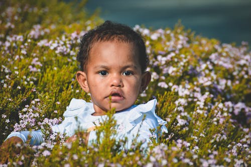 A Child Standing on Green Grass Field