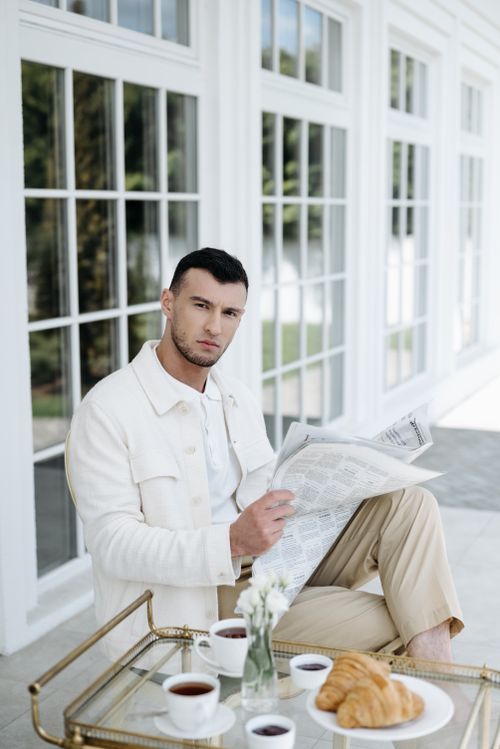 Free Man sitting outdoors with coffee and newspaper, a serene morning routine. Stock Photo