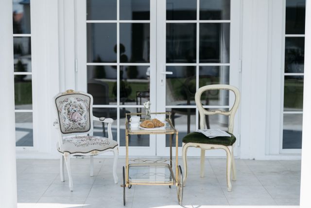 Terrasse ensoleillée avec fauteuils blancs et desserte pour le petit-déjeuner en extérieur
