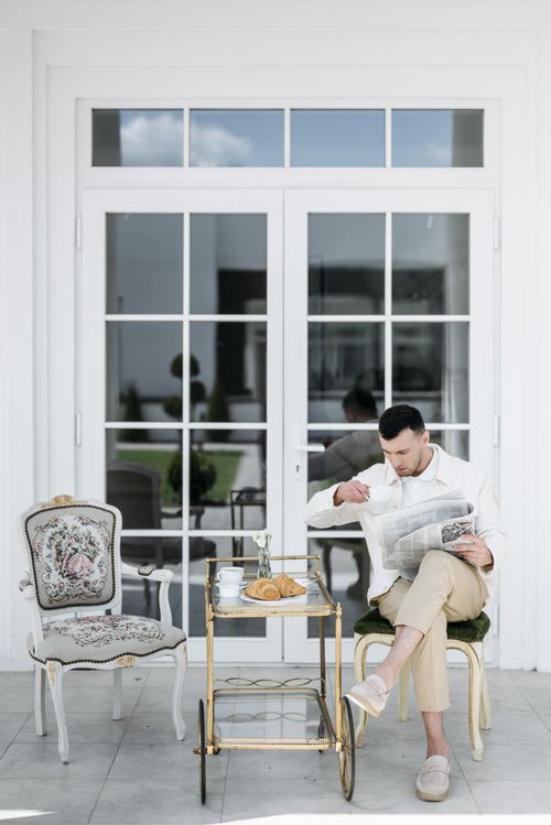 Free Man enjoying breakfast on a terrace with coffee, croissants, and newspaper. Stock Photo