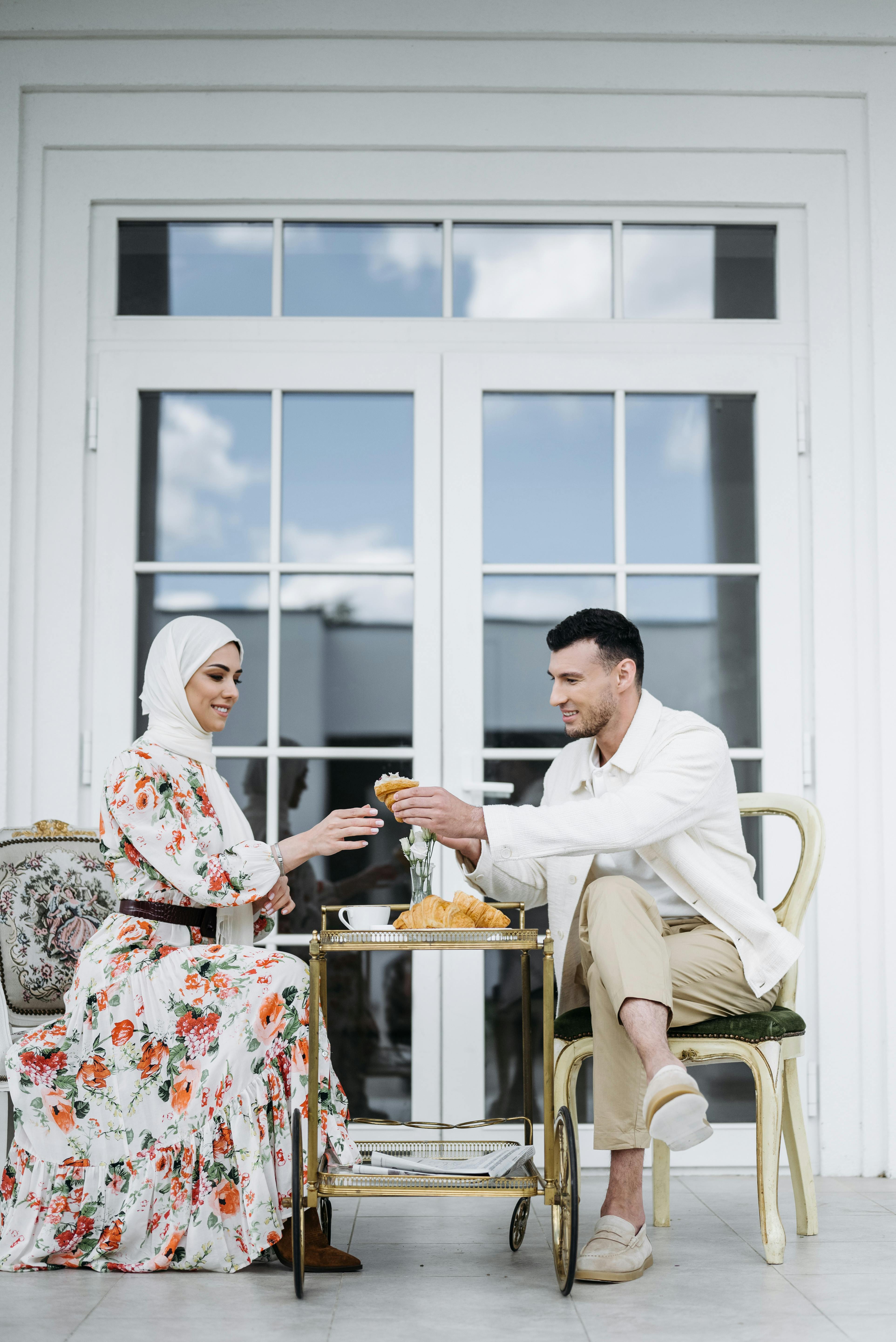 man in white dress shirt and woman in floral maxi dress sitting in the patio having breakfast