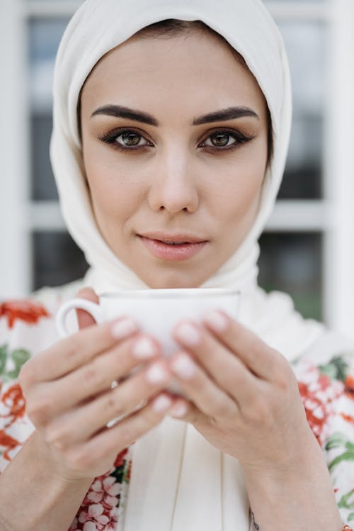 A Woman in White Hijab Holding a Cup of Coffee