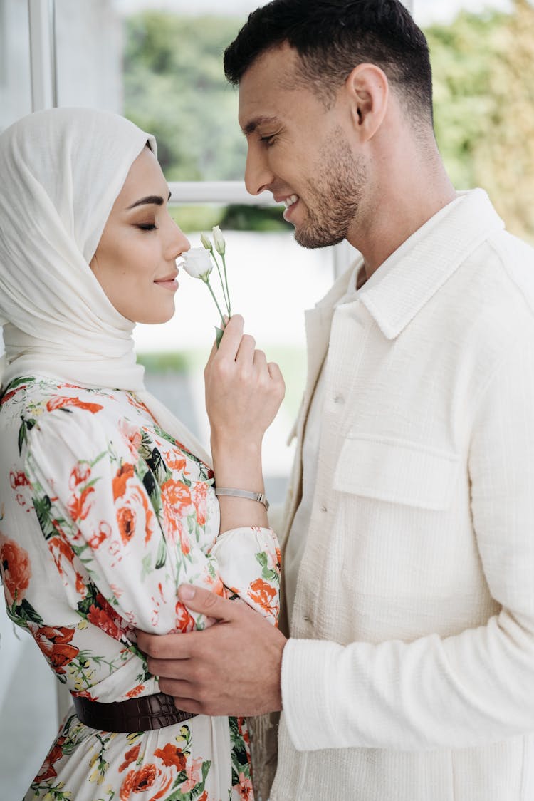 Woman Smelling Flowers In Front Of A Man