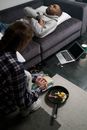 Sad Man Lying on a Sofa while Woman Getting Dirty Dishes