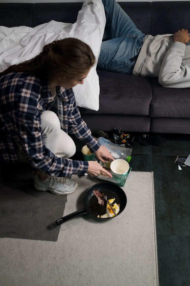 A Woman In Plaid Long Sleeves Cleaning Mess On The Floor