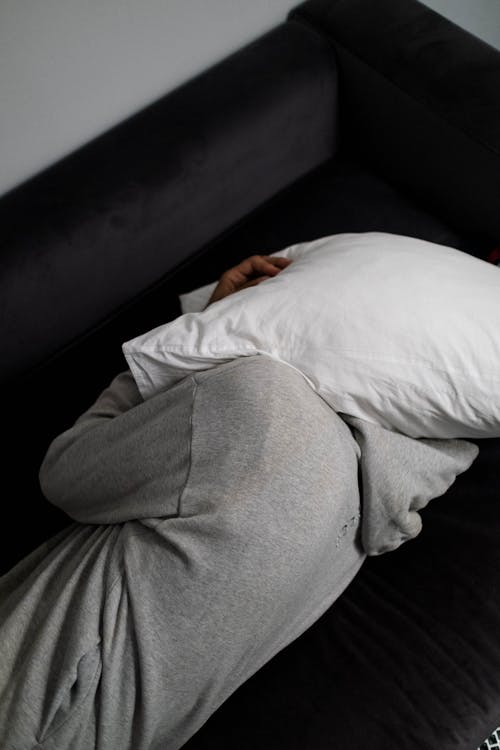 Free A Man Covering His Head with a Pillow While Lying on the Bed Stock Photo