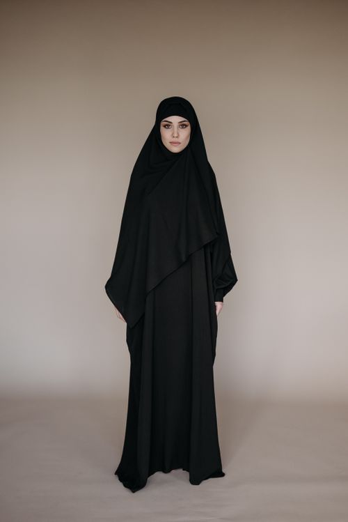 Free Full-body portrait of a woman wearing a hijab standing against a neutral backdrop. Stock Photo