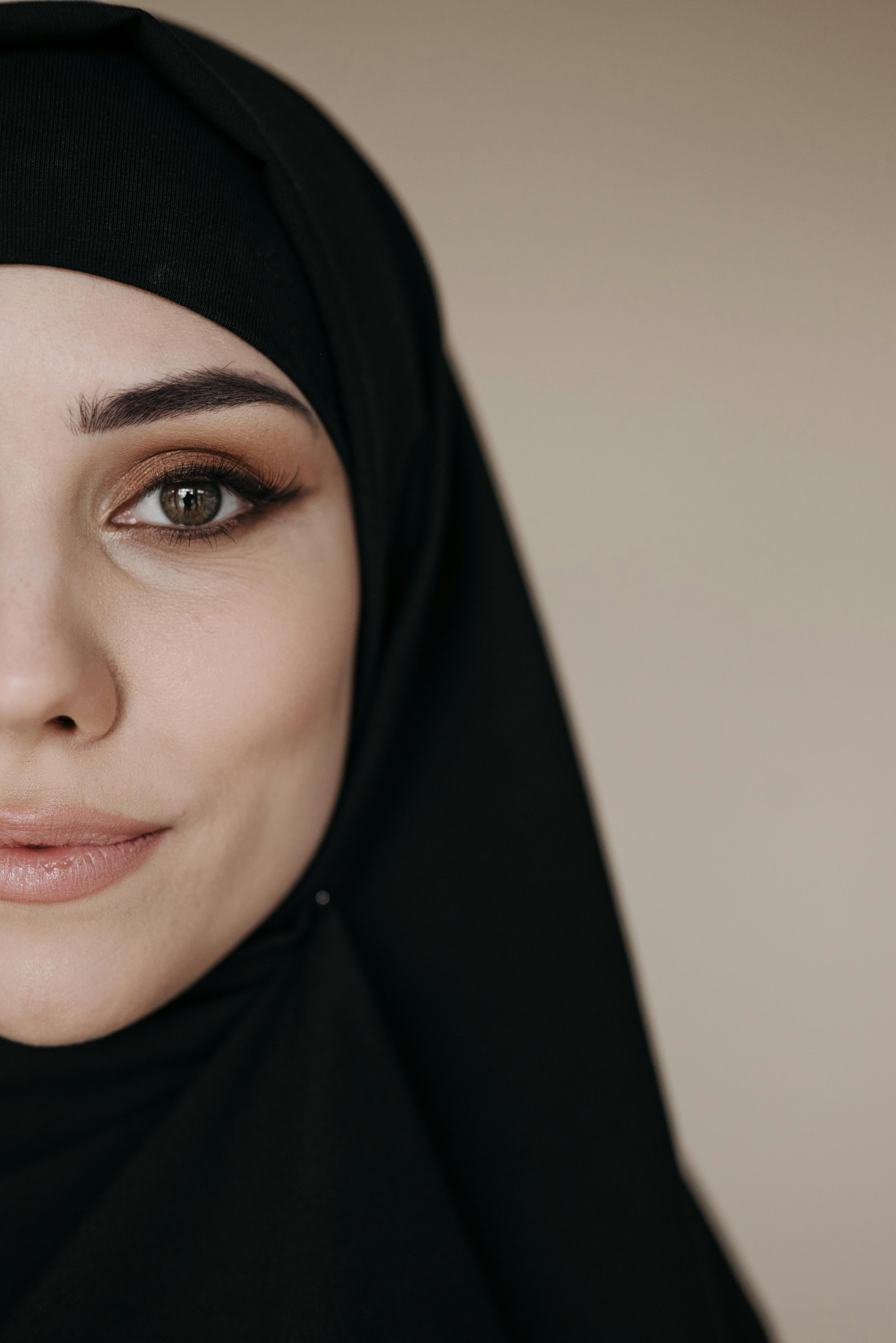 Close-up portrait of a woman wearing a black hijab, highlighting her eye makeup.