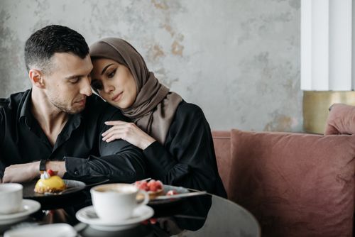 Free A loving Muslim couple sitting together in a cozy café setting, enjoying a serene moment. Stock Photo