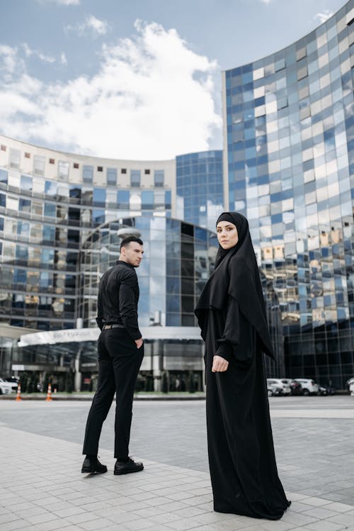 Man and Woman Wearing Black Clothes Standing Near Tall Buildings