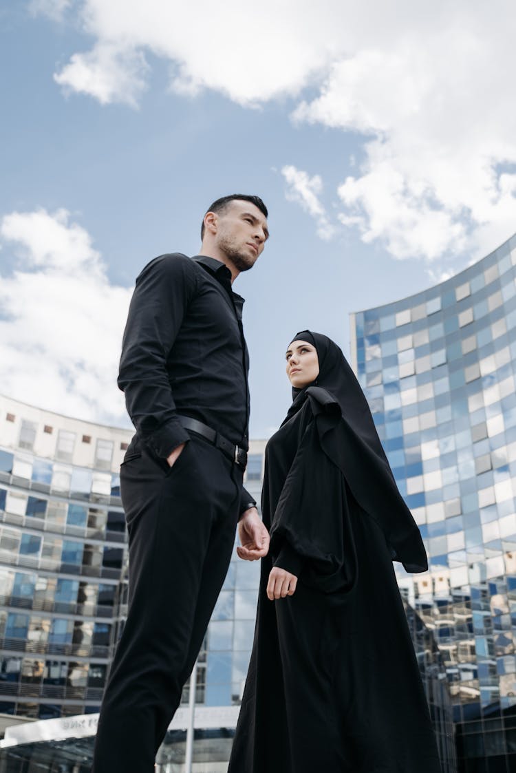 A Man In Black Long Sleeves Standing Beside A Woman In Black Abaya