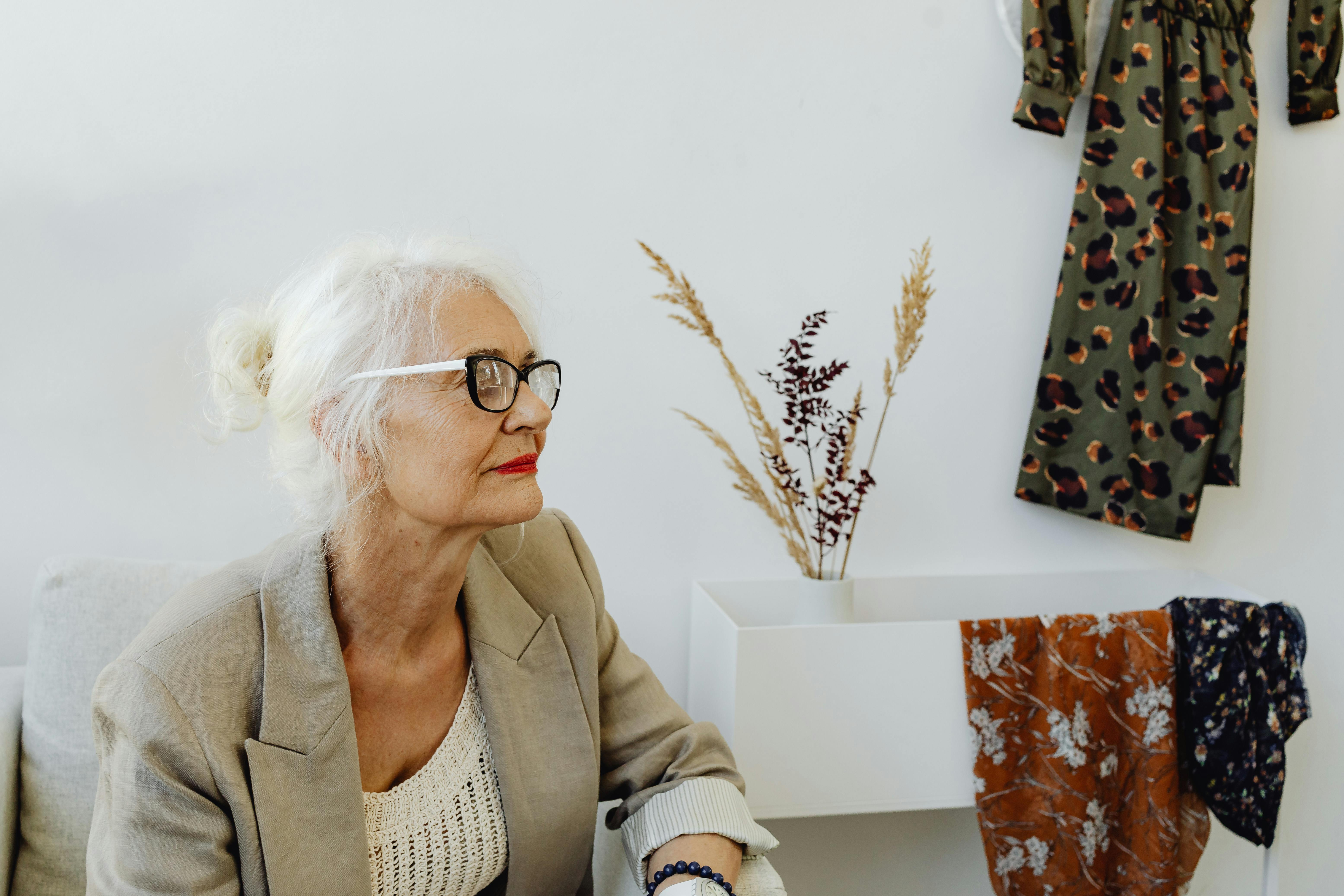 Free Stylish senior woman with white hair and glasses in a modern indoor setting. Stock Photo