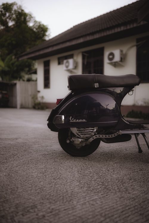 Free A classic Vespa scooter parked on a quiet residential pavement, showcasing its vintage charm. Stock Photo