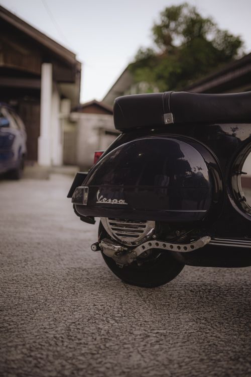 Free Close-up of a classic Vespa scooter parked outdoors on a concrete surface. Stock Photo