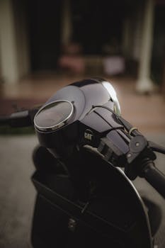 Detailed view of a scooter's handlebar and speedometer with a blurred background, emphasizing design and structure.