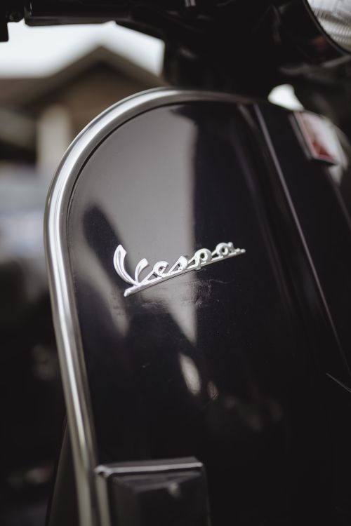 Free Detailed view of a Vespa scooter logo with a glossy black surface. Stock Photo