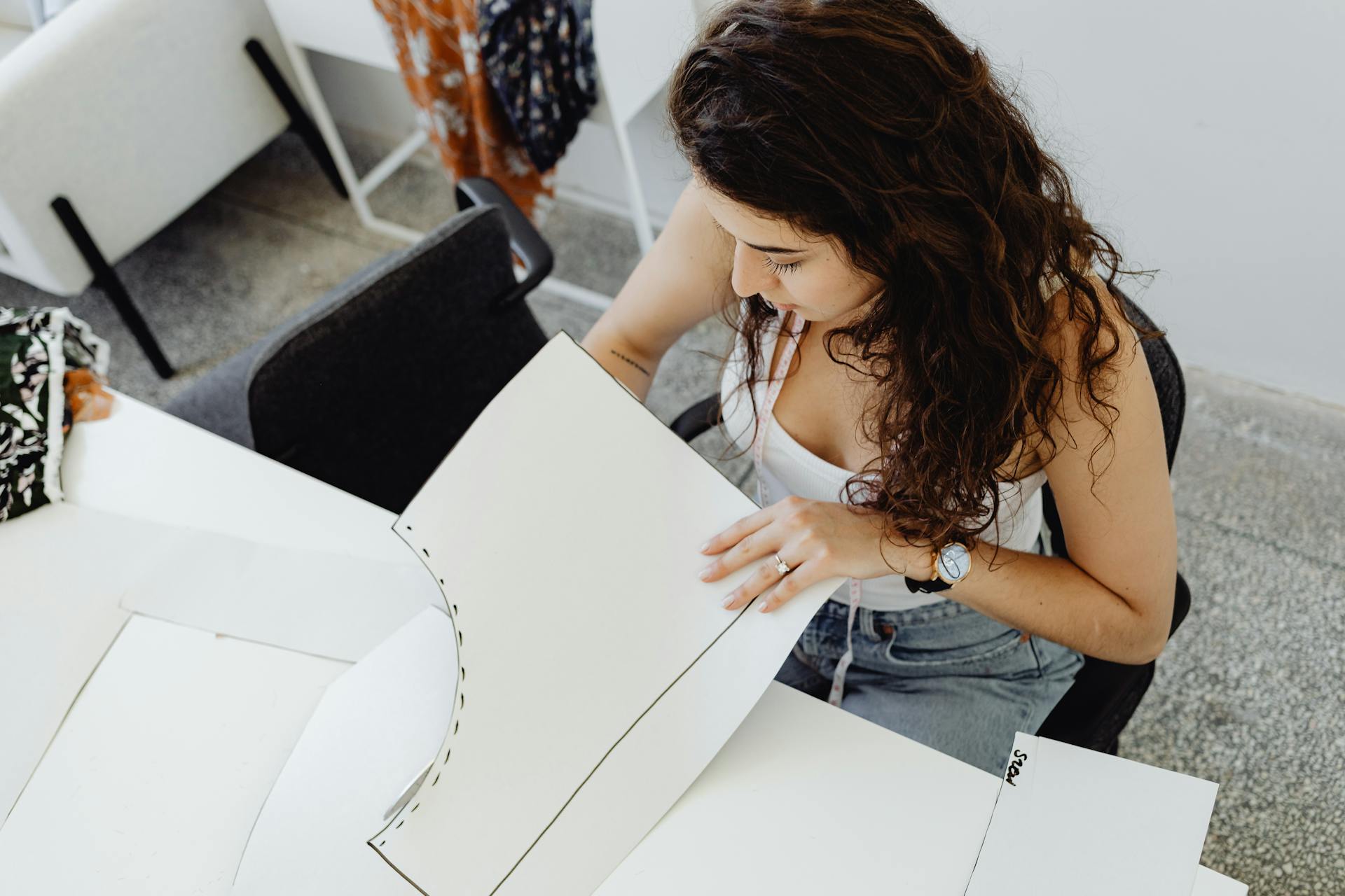 A young woman in a modern workspace working on sewing patterns. Perfect for small business and creativity themes.