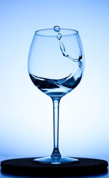 A dynamic splash captured in a clear wine glass, illuminated by blue light, creating an artistic effect.