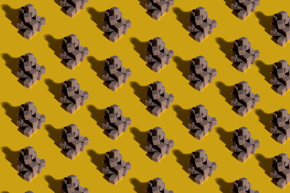Artistic arrangement of brown sugar cubes creating a modern pattern on a vibrant yellow background.