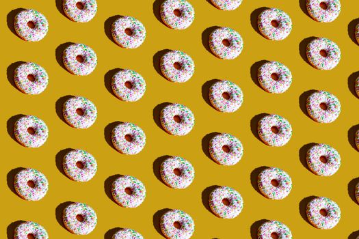 Bright donuts with sprinkles arranged in a playful pattern on a vibrant yellow backdrop.