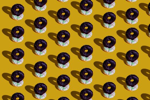 Colorful variety of donuts arranged in a vibrant pattern on a yellow background.