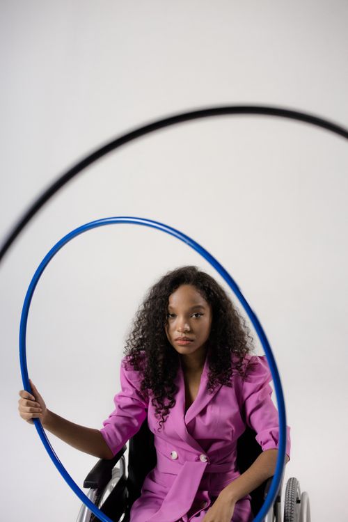 Free Young black woman in pink suit with hula hoop, seated in wheelchair. Stock Photo