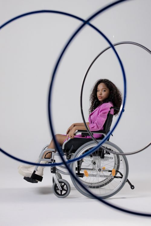 Free Portrait of a black woman with curly hair in a wheelchair, surrounded by hula hoops. Stock Photo