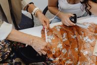 Person in White and Brown Floral Dress Holding Black Smartphone