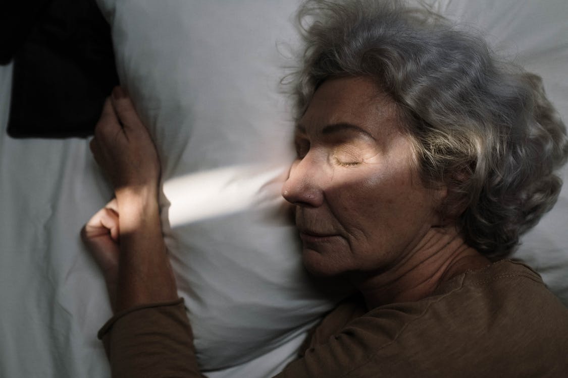 sleep tips Free Serene image of elderly woman resting peacefully on pillow with sunlight grazing her face. Stock Photo